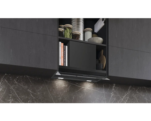 Küchenszene mit Dunstabzugshaube unter Hängeschrank mit Kochbüchern und Küchenutensilien