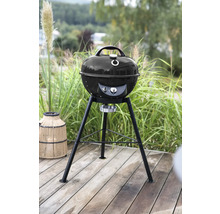 Kugelgrill auf einer Terrasse vor grüner Vegetation