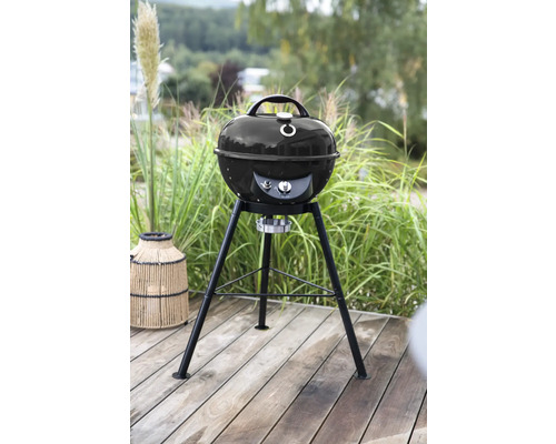 Kugelgrill auf einer Terrasse vor grüner Vegetation