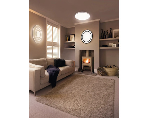 Wohnzimmer mit Sofa, Kaminofen, Teppich und verschiedenen Lampen