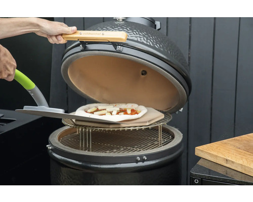 Barbecue en céramique avec pizza sur pierre à pizza et pelle à pizza