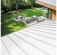 Vue d'ensemble d'un jardin avec coin barbecue, coin salon et robot tondeuse.