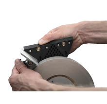 Person schärft Werkzeug mit Schleifmaschine