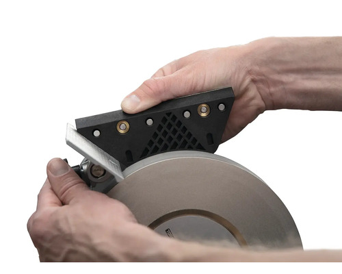 Person schärft Werkzeug mit Schleifmaschine