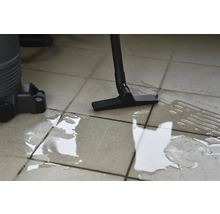 Aspirateur eau et poussière en cours d'utilisation sur sol carrelé avec de l'eau