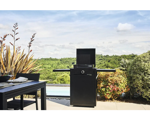 Außenszene mit Grill, Gartentisch und Pflanzen im Freien.