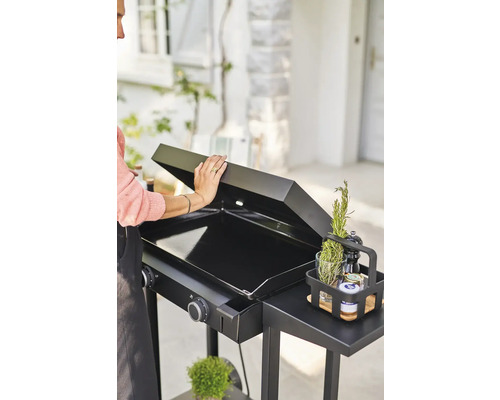 Schwarzer Grill mit Deckel, Seitenablage und Gewürzen im Garten