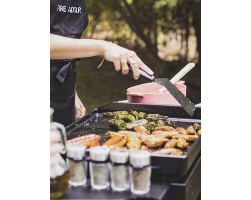 Eine Person grillt Paprika und Fleisch auf einem Grill im Freien.
