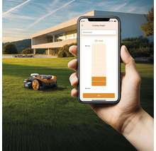 Ein Roboter-Rasenmäher auf einer Wiese wird per Smartphone-App gesteuert.