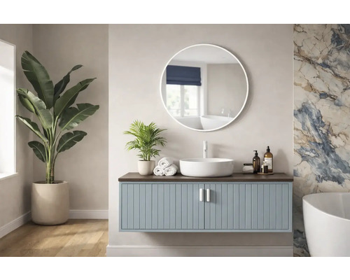 Helles Badezimmer mit Waschtisch, rundem Spiegel und Zimmerpflanzen.