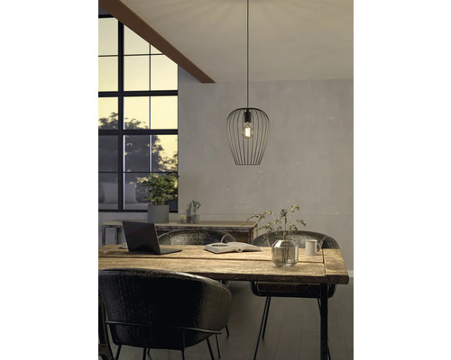 Szene mit einer Pendelleuchte aus Metall über einem Holztisch in einem hellen Raum