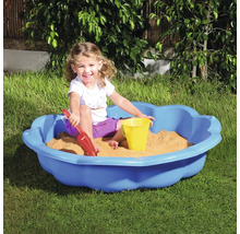 Kind spielt in einem blauen Sandkasten mit Sandspielzeug im Garten