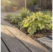 Gartenszene mit Holzterrasse und bepflanztem Beet