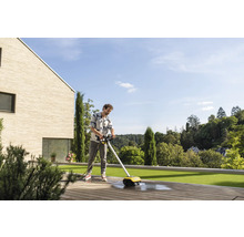 Mann reinigt Holzterrasse mit einem elektrischen Flächenreiniger.