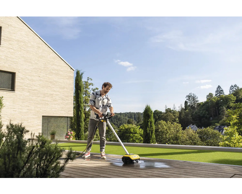 Mann reinigt Holzterrasse mit einem elektrischen Flächenreiniger.