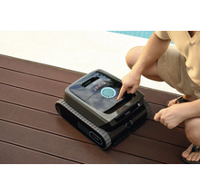 Robot de nettoyage de piscine Aiper sur une terrasse en bois avec une personne appuyant sur un bouton