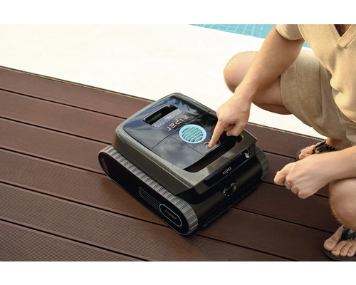 Robot de nettoyage de piscine Aiper sur une terrasse en bois avec une personne appuyant sur un bouton