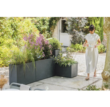 Vue de jardin avec bacs à plantes gris et une femme portant un plateau
