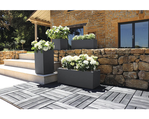 Aussenaufnahme von rechteckigen und quadratischen Pflanzkästen mit Blumen vor einem Gebäude.