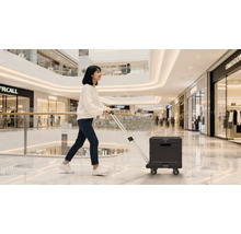 Frau zieht einen schwarzen Mehrzweckwagen in einem Einkaufszentrum.