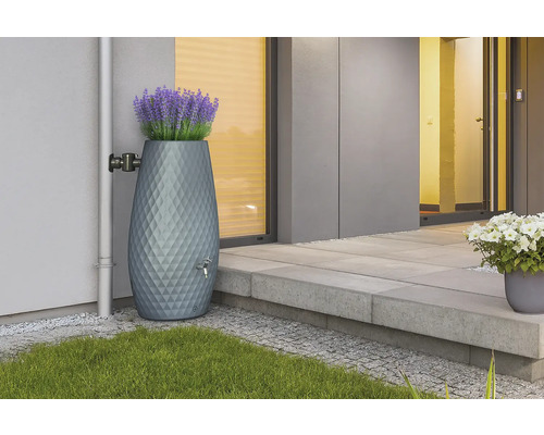 Récupérateur d'eau de pluie gris moderne avec motif en losange et bac à fleurs intégré avec lavande contre un mur de maison près d'une descente.