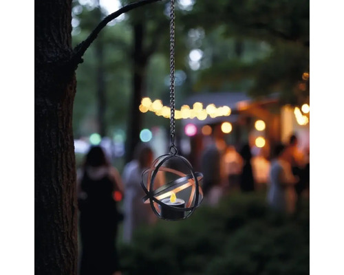 Hängende Laterne mit Metallgestell und Teelicht im Garten.