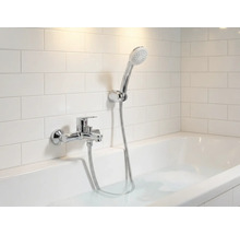 Salle de bain avec baignoire, robinetterie et douchette devant des carreaux muraux