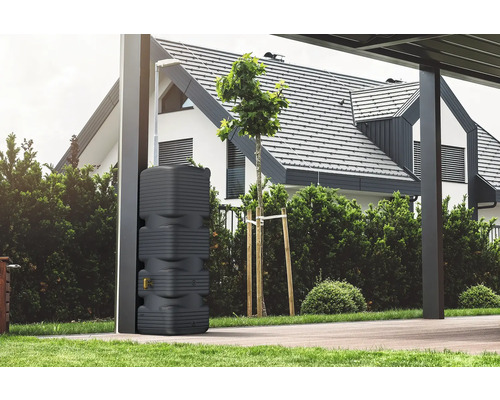 Regenspeicher mit Lamellenstruktur und Auslaufhahn in einem modernen Garten neben einem Pfeiler vor einem Wohnhaus.