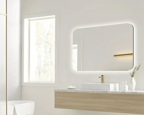 Salle de bain lumineuse avec miroir éclairé, lavabo et fenêtre.