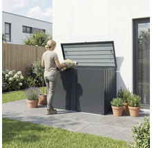 Une femme remplit un coffre de jardin avec un sac de terreau dans le jardin.