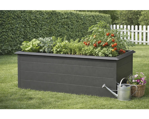 Jardinière surélevée avec salade, herbes aromatiques et plants de tomates, arrosoir et panier de fleurs sur une pelouse