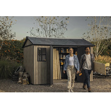 Scène de jardin avec remise à outils, une femme et un homme portant des outils et du bois