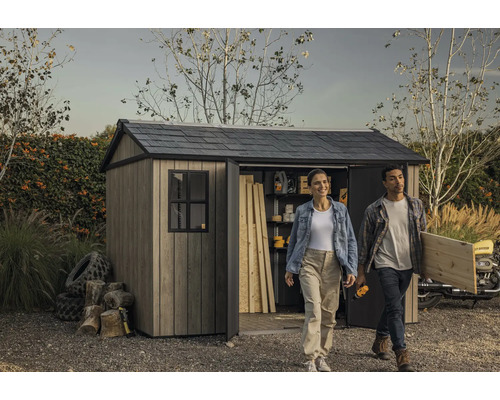 Scène de jardin avec remise à outils, une femme et un homme portant des outils et du bois