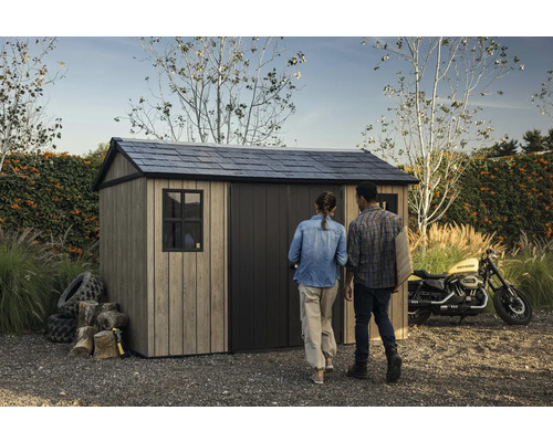 Abri de jardin avec toit à deux pans et deux personnes dans le jardin.