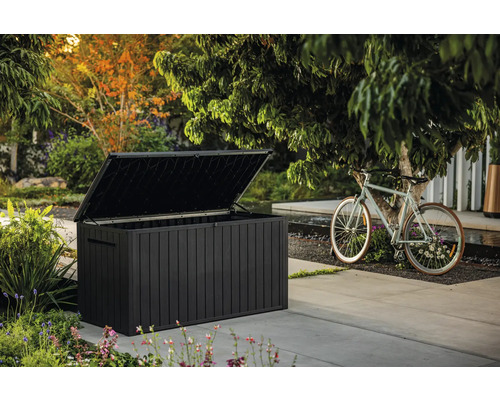 Coffre de jardin foncé ouvert à côté d'un vélo à l'extérieur.