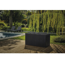 Scène de jardin avec piscine, chaises longues et grand coffre de rangement en plastique sur une terrasse en bois
