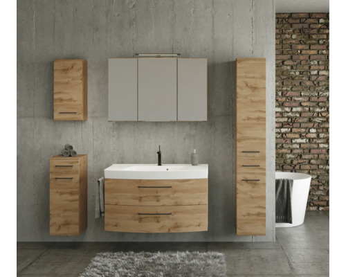 Modernes Badmöbel-Set in Eichenoptik mit weißem Waschtisch, Spiegelschrank, Hochschrank und Beistellschränken vor einer Betonwand.