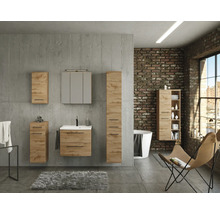 Ensemble de meubles de salle de bains aspect chêne devant un mur en béton, avec meuble sous-vasque, armoire de toilette et éléments muraux.