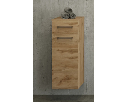 Meuble de salle de bain suspendu aspect chêne avec un tiroir, une porte et des poignées noires sur un mur en béton.