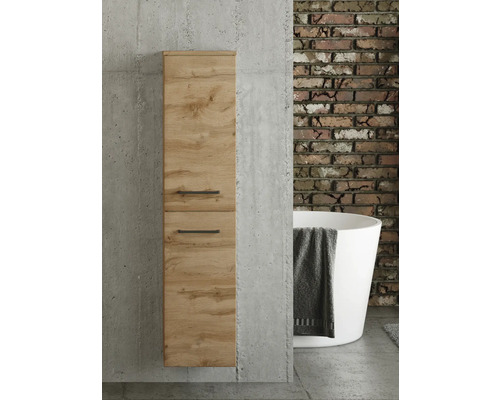 Colonne de salle de bains aspect chêne avec poignées noires sur mur en béton. En arrière-plan, mur en briques et baignoire îlot.