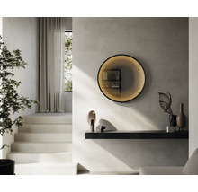 Salon lumineux avec escalier, plante, étagère murale et miroir rond éclairé