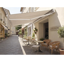 Extérieur d'un café avec un auvent et des sièges sur une rue pavée