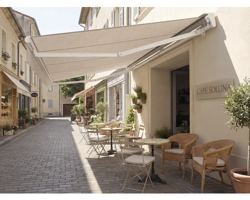 Extérieur d'un café avec un auvent et des sièges sur une rue pavée