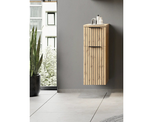 Colonne de salle de bains suspendue aspect bois avec lattes et poignées noires dans une salle de bains moderne et lumineuse à côté d'une plante.