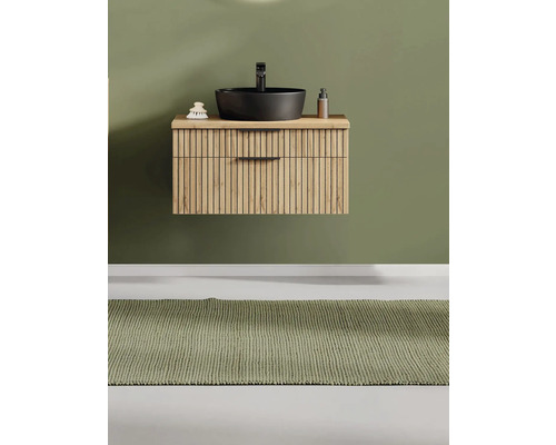 Modernes organisiertes Badezimmer mit wandhängendem Waschbeckenunterschrank aus Holz, Lamellenfront, schwarzem Aufsatzwaschbecken und Teppich.