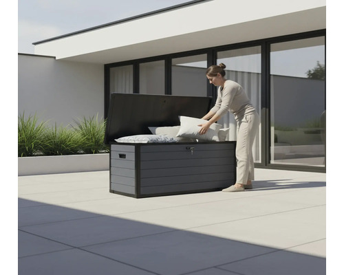 Une femme range des coussins dans un coffre de jardin gris à l'extérieur