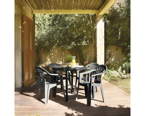 Scène de jardin avec une table de jardin noire et quatre chaises de jardin assorties sur une terrasse