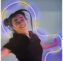 Une femme souriante devant un mur avec un ruban LED flexible et lumineux de forme incurvée.