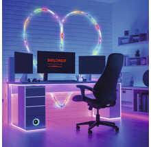 Salle de jeux moderne avec bureau, écrans et Briloner Logo. Un ruban lumineux forme un cœur sur le mur en briques derrière le bureau.