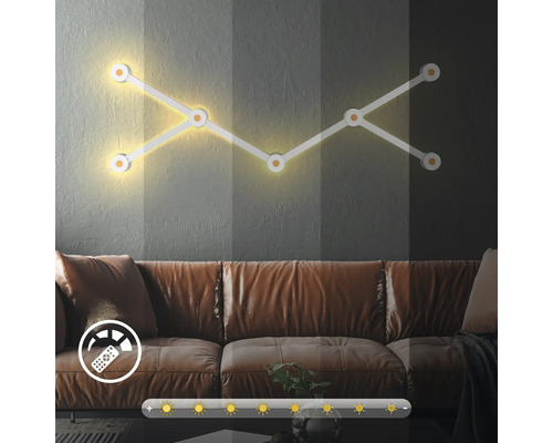 Modulare LED Wandleuchte mit Dimmfunktion über einem Sofa im Wohnzimmer inklusive Symbolen für Fernbedienung und Helligkeitssteuerung.